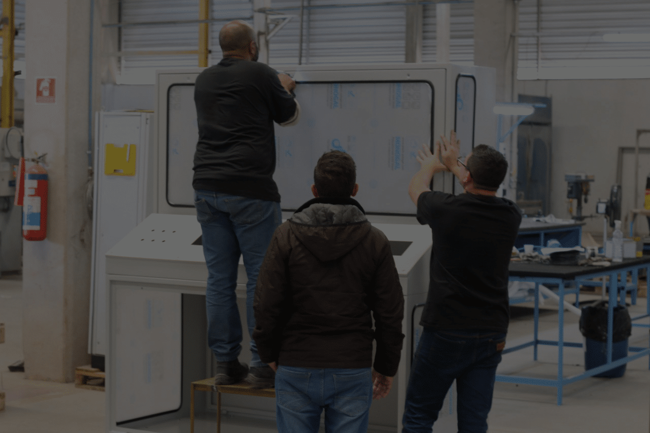 Equipe Rocktron na oficina de montagem, trabalhando sobre a estrutura de um painel elétrico.