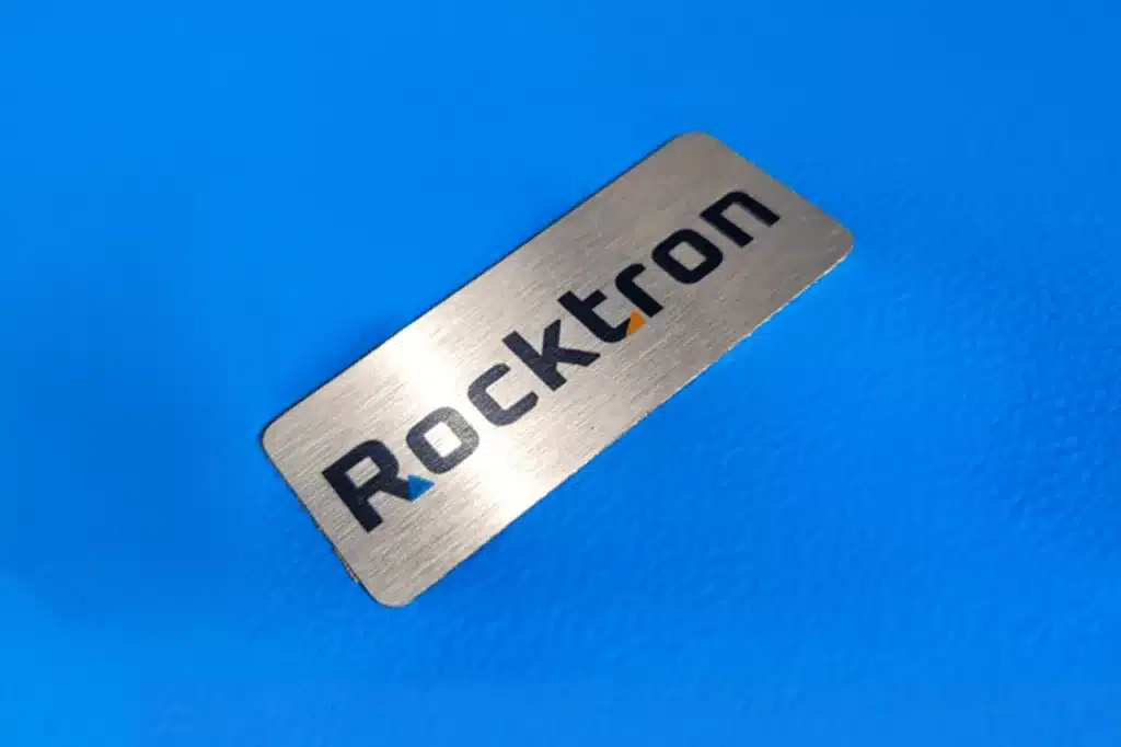 Plaqueta de identificação Rocktron em aço escovado, com a marca gravada.