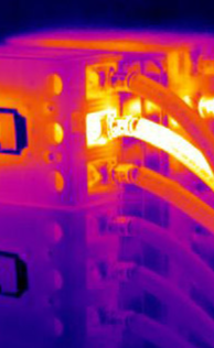 Imagem termográfica de barramento e cabos, com pontos quentes em amarelo sobre fundo magenta.